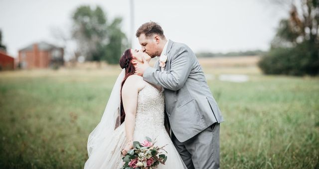 bride and groom kissing in a grassy field