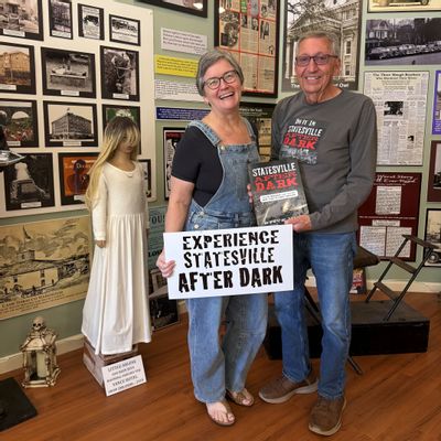 Cindy Sutton and Steve Hill smile while holding his book, Statesville After Dark, inside the Statesville Historical Collection.