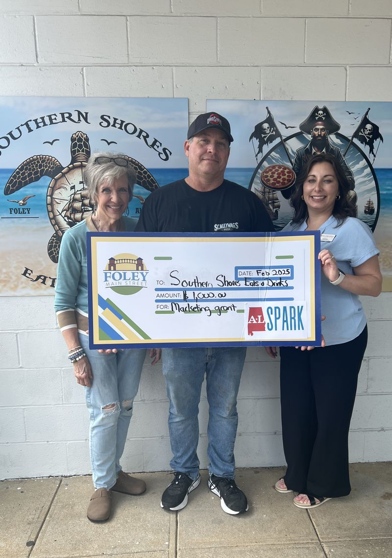 Southern Shores Eats & Drinks  is a 2025 Winner of a $1,000 marketing grant through ALSPARK.. Accepting the check is owner Mark Lindsey. .Also pictured are Foley Main Street board members Deborah Mixon and Sabrina May.