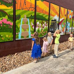 Children look for the five cats hidden in the Foley Main Street community mural in Downtown Foley