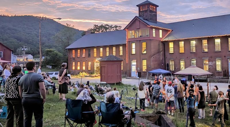Brick Mill Building with People Listening to a Band