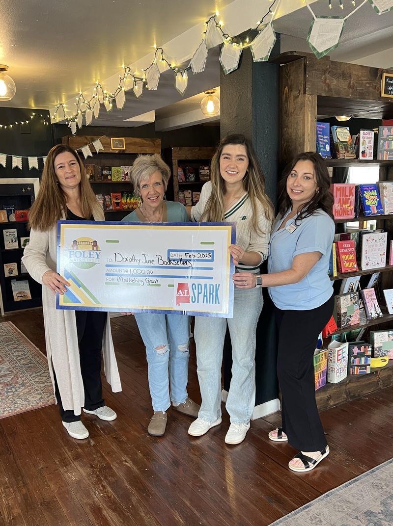 Dorothy June Booksellers is a 2025 Winner of a $1,000 marketing grant through ALSPARK. Accepting the check is owner Reide Irwin and her mother . Also pictured are Foley Main Street board members Deborah Mixon and Sabrina May.