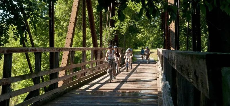 A family bikes across a wooden bridge on the Root River State Trail in Lanesboro, Minnesota.