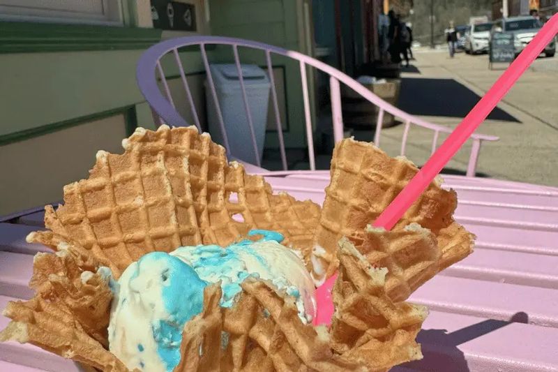 Waffle bowl filled with blue and white ice cream and waffle pieces on a pink outdoor table along Main Street in Lanesboro, Minnesota.