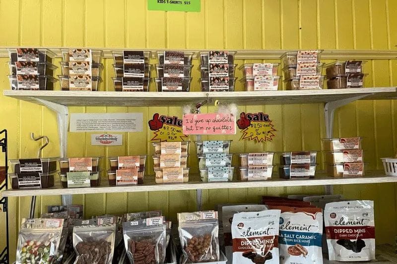 Shelves of packaged sweet treats and candies displayed inside the Whalan Depot, with assorted chocolates, baked goods, and snack bags arranged against a bright yellow wall in Whalan, Minnesota.