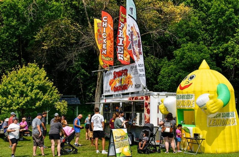 People lining up at a concession stand selling pizza, lemonade, and more during Buffalo Bill Days in Lanesboro, MN