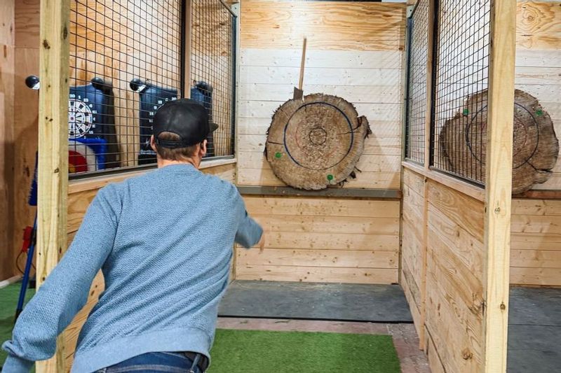 A man throws an axe at a target made out of a tree stump at an indoor axe throwing facility in Lanesboro, MN