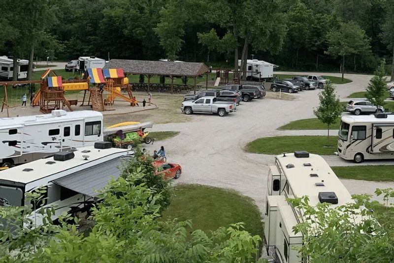 RVs and vehicles are parked throughout Eagle Cliff Campground, with a colorful playground, picnic shelter, and wooded surroundings visible in this family-friendly camping area near Lanesboro, Minnesota.