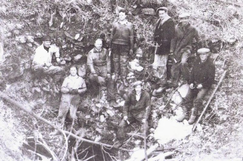 A historic black-and-white photograph shows a group of early explorers standing inside Niagara Cave, documenting the site during its early discovery period near Lanesboro, Minnesota.
