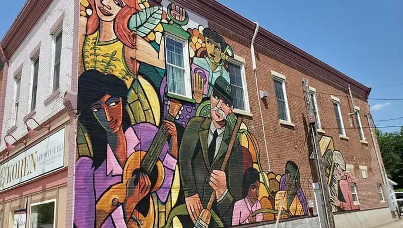 A colorful mural painted on the side of a brick building in downtown Lanesboro, depicting musicians and performers in a stylized, vibrant design that reflects the town’s arts and cultural heritage.