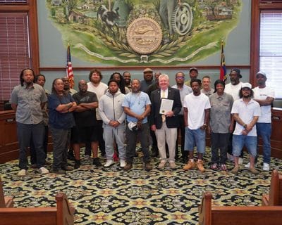 Sanitation workers stand with Mayor Doug Hendrix in the Statesville City Council Chambers during the June 15, 2026 City Council meeting. Mayor Hendrix holds a proclamation recognizing June 15–20, 2026, as National Waste and Recycling Workers Week, honoring the essential contributions of sanitation and recycling employees who help keep the community clean, safe, and healthy. The group is gathered beneath the City of Statesville seal, commemorating the recognition.