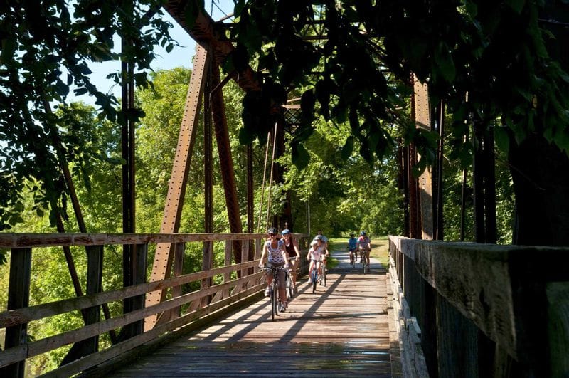 A family bikes across a wooden bridge on the Root River State Trail in Lanesboro, Minnesota.