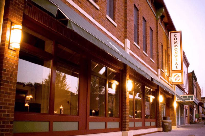 Exterior of the Commonweal Theatre Company building in downtown Lanesboro, Minnesota, glowing with warm lights along a brick storefront at dusk.