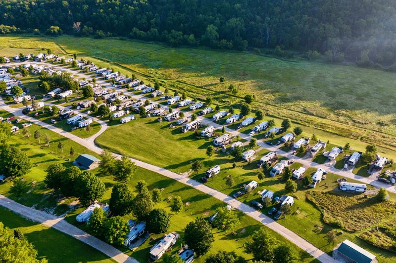An aerial view shows rows of RV sites at the Old Barn Resort near Lanesboro, Minnesota, with campers set among green fields, trees, and open countryside.