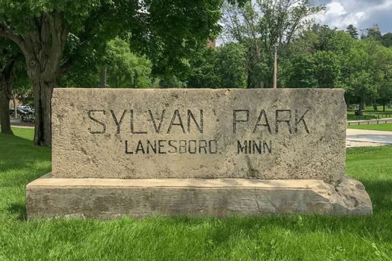 Stone entrance sign reading “Sylvan Park, Lanesboro, Minn.” surrounded by grass and trees in Lanesboro, Minnesota.