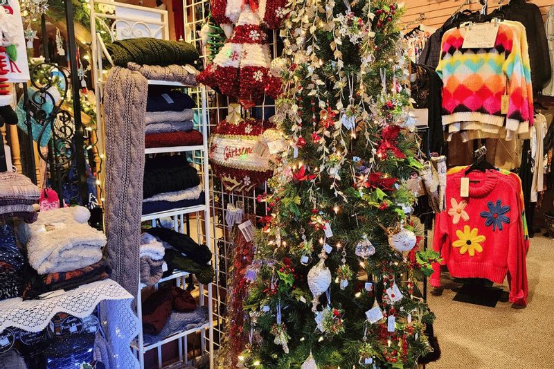 A decorated Christmas tree surrounded by colorful clothing and gift items inside E2 Boutique in downtown Lanesboro during the holiday shopping season.