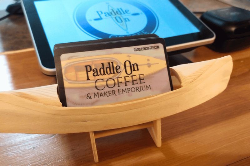 Paddle On Coffee & Maker Emporium gift cards displayed in a small wooden canoe holder on the café counter in Lanesboro.
