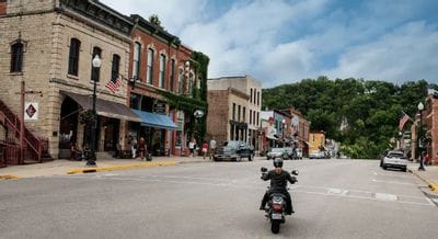 Motorcyclist riding through historic downtown Lanesboro, Minnesota, lined with brick storefronts and local shops.