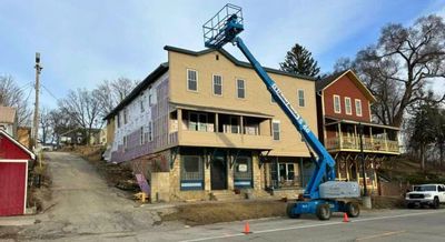 Exterior of the Blue Hotel building in Lanesboro undergoing renovation, with a lift raised to the roof and construction work visible along the street.