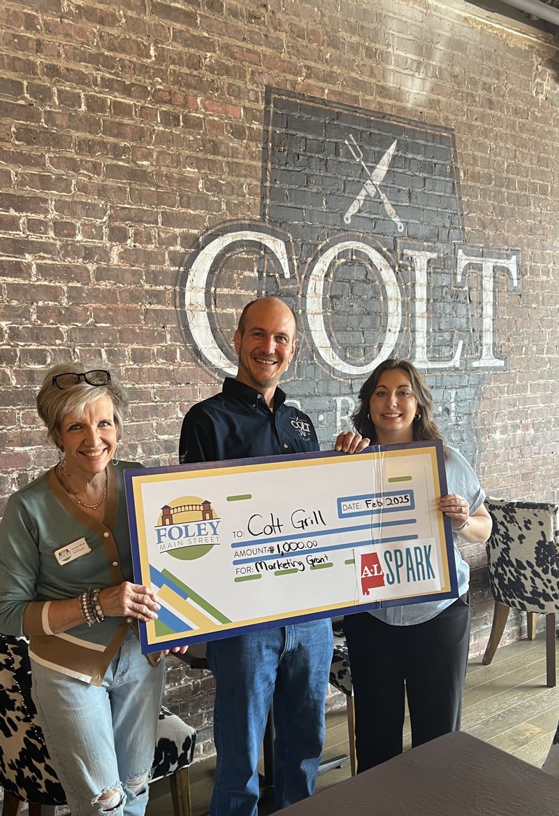 Colt Grill BBQ & Grill is a 2025 Winner of a $1,000 marketing grant through ALSPARK. Accepting the check is Manager Nick Parker. Also pictured are Foley Main Street board members Deborah Mixon and Sabrina May.