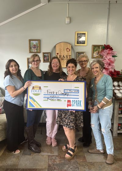 Feast & Company is a 2025 Winner of a $1,000 marketing grant through ALSPARK. Owner Mary Garcia and her crew accepted the check. Foley Main Street board members Deborah Mixon and Sabrina May presented the check.