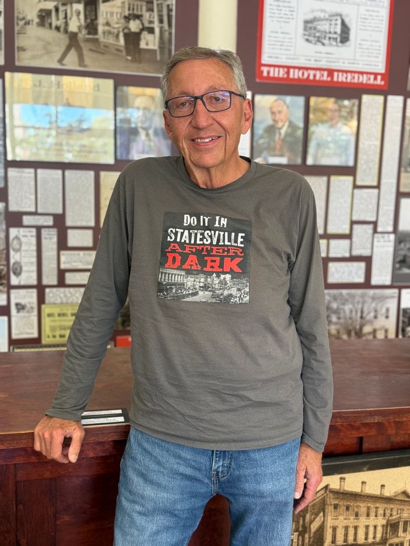 Historian Steve Hill stands inside the Statesville Historical Collection wearing a Statesville After Dark shirt.