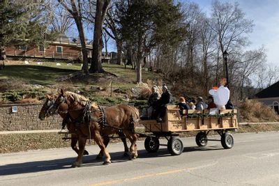 A horse-drawn wagon carries bundled riders through downtown Lanesboro during an Experience the Magic winter event, with draft horses pulling the wagon along the street.