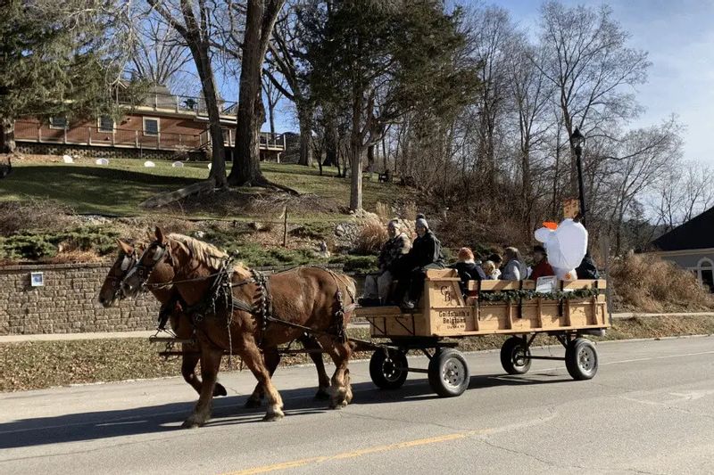 A horse-drawn wagon carries bundled riders through downtown Lanesboro during an Experience the Magic winter event, with draft horses pulling the wagon along the street.
