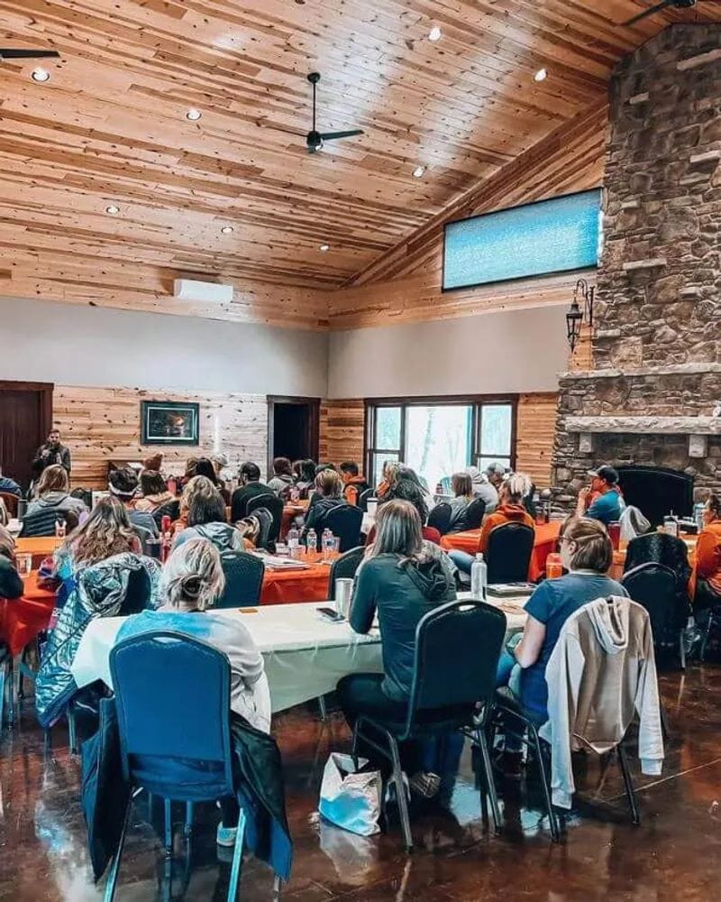 A group gathered for a meeting or event inside a rustic lodge-style event space at Cedar Valley Resort.