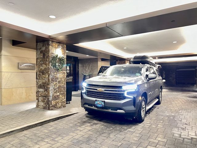 Blue Sky Limo Chevrolet Suburban with rooftop ski box at a Vail residence entrance in winter