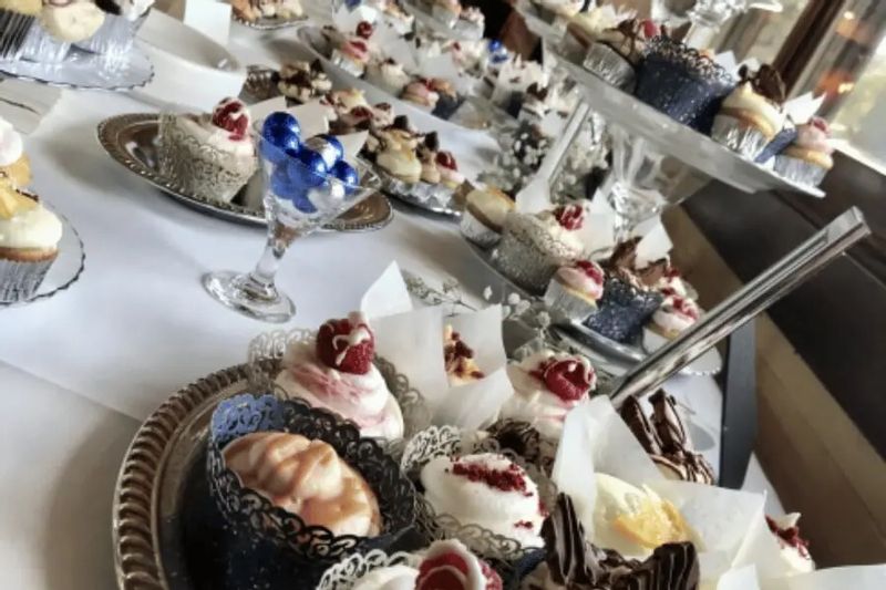 An elegant dessert display at the Cedar Valley Retreat Center features tiers of individually plated cupcakes and pastries, decorated with frosting, fruit, and chocolate accents, arranged for a special event or celebration.