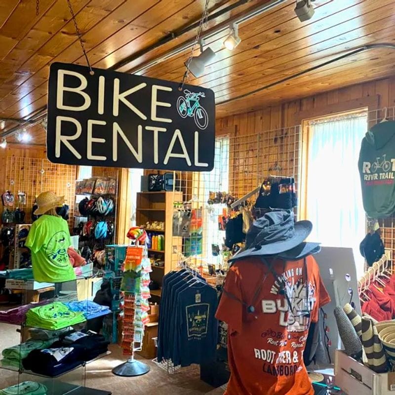 Interior of a bike rental shop in Lanesboro, Minnesota, featuring a “Bike Rental” sign, cycling gear, and Root River Trail apparel in Bluff Country