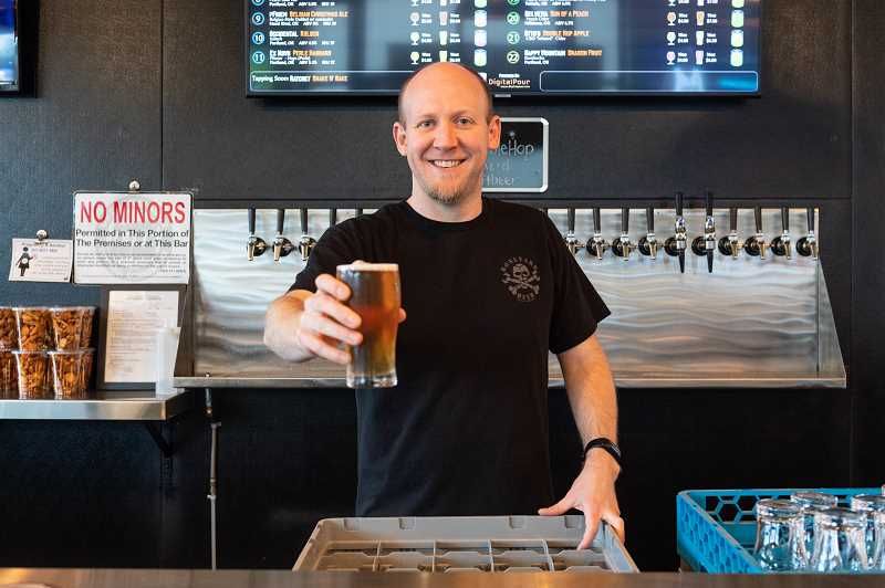 PMG PHOTO: CHRISTOPHER OERTELL – Neal Glaske holds a glass of beer behind the counter at the Noble Hop Bierhouse in Hillsboro. It also offers wine and nonalcoholic beverages like kombucha and CBD drinks.
