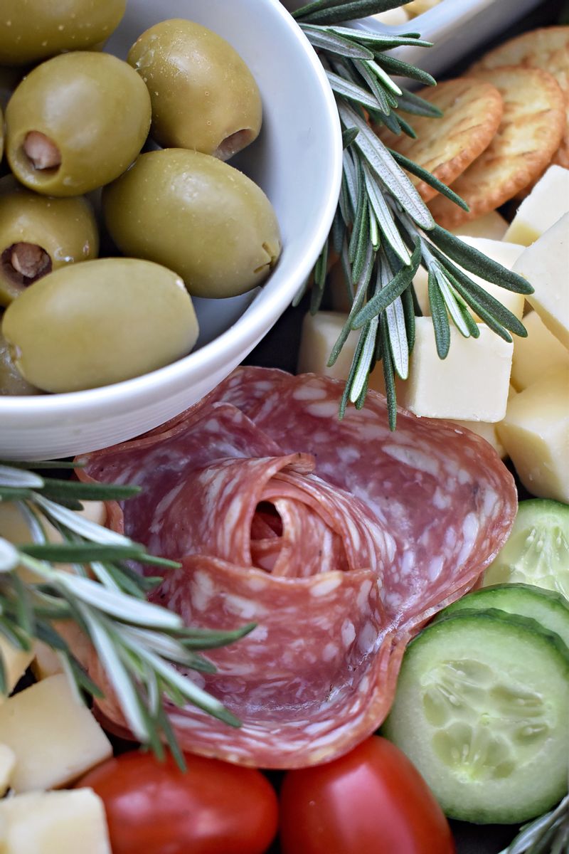 Close up charcuterie board with olives, and decorated deli meats