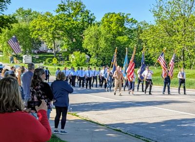 Memorial Day parade with spectators watching from the sidewalk and members of the Lanesboro American Legion marching while holding flags
