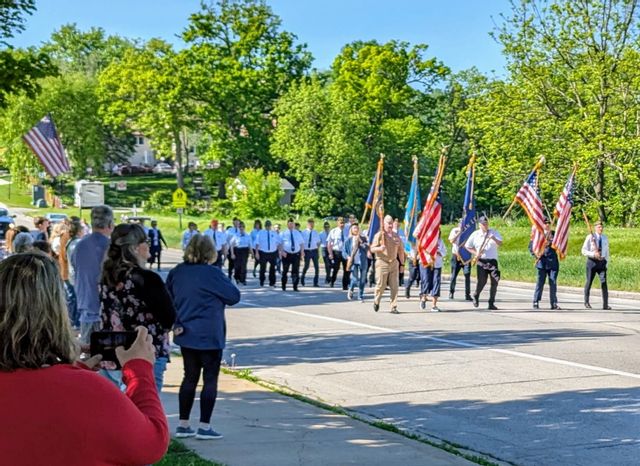 Memorial Day parade with spectators watching from the sidewalk and members of the Lanesboro American Legion marching while holding flags