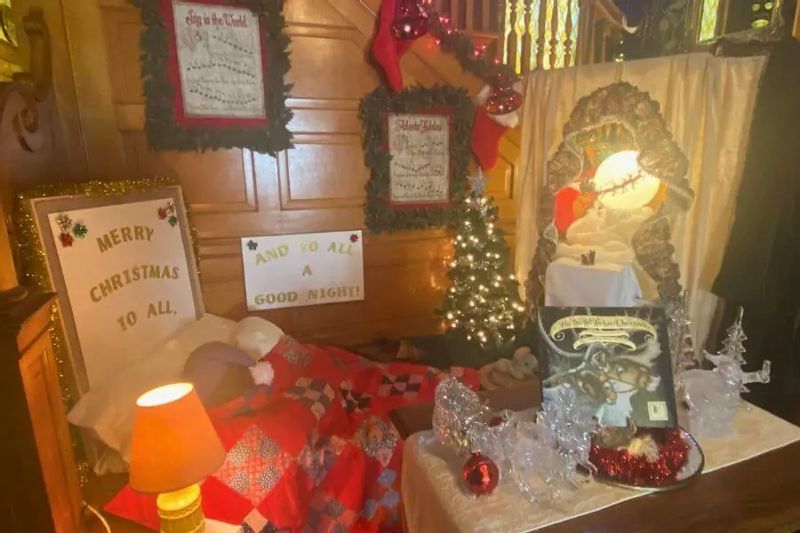 A whimsical Christmas bedroom display at Oakenwald Terrace during a holiday open house, featuring festive signs, twinkling lights, and a cozy bed decorated for the season.