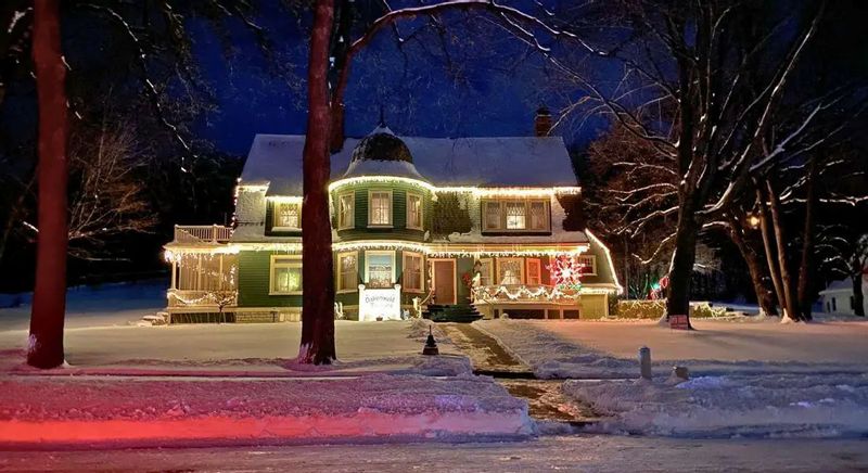 The exterior of Oakenwald Terrace in Lanesboro decorated with Christmas lights, glowing warmly against the snow on a winter evening.