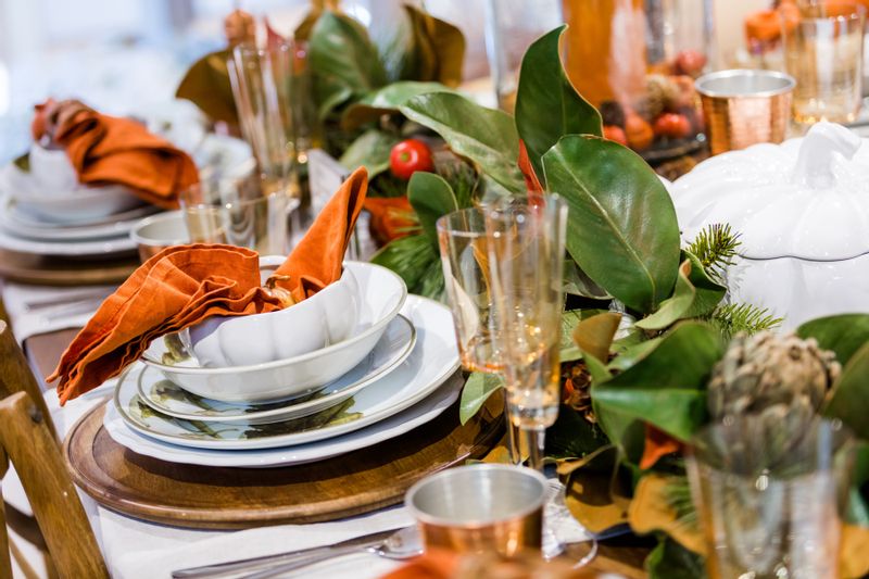 Table decorated for Thanksgiving with Magnolia leaves and white dishes