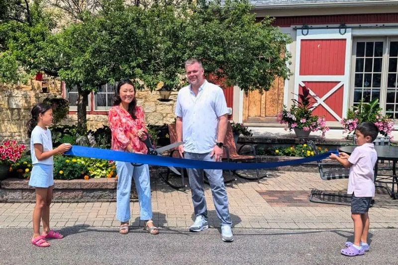 The Stone Mill Hotel & Suites owners and their children hold a ribbon during a ribbon-cutting ceremony outside the historic Stone Mill building in Lanesboro.