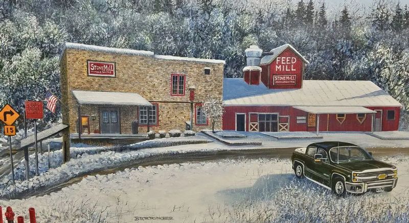 A winter painting of the Stone Mill Hotel & Suites and nearby Feed Mill buildings in Lanesboro, showing snow-covered historic structures and a pickup truck parked along the road.