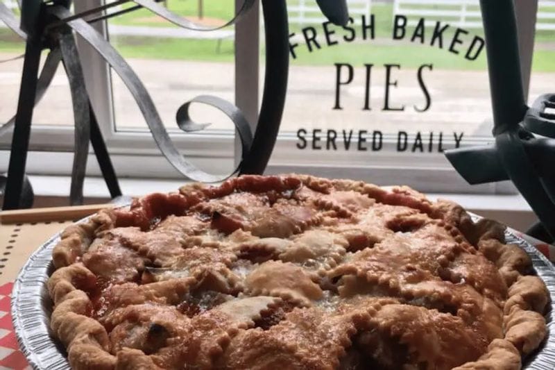 Freshly baked fruit pie on a table by a window reading “Fresh Baked Pies Served Daily” inside the Aroma Pie Shoppe in Whalan, Minnesota.
