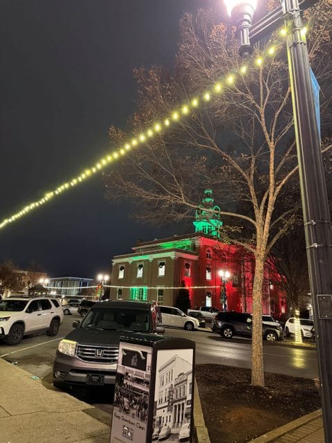 string lights hanging on downtown square for Christmas with courthouse in background