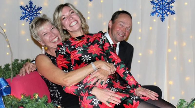 Three people smiling and laughing together at the Lanesboro Annual Dinner & Dance, seated in front of festive winter décor with snowflake decorations and string lights in the background.