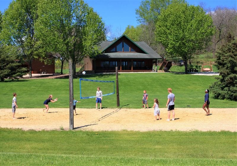 Children and adults play volleyball on a sand court at Cedar Valley Resort in Whalan, Minnesota.