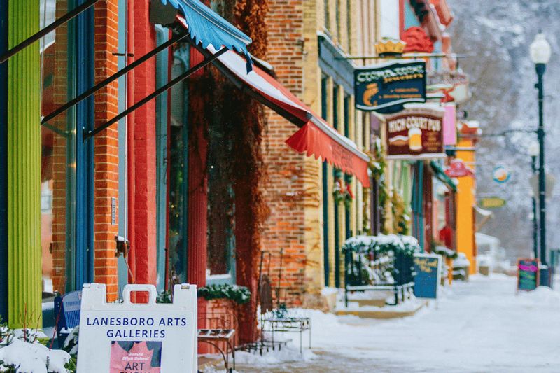 Winter view of downtown Lanesboro, MN, featuring historic storefronts, gallery signs, and snow-covered sidewalks.