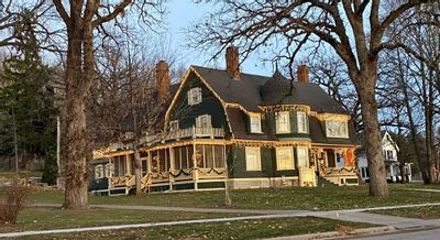 The exterior of Oakenwald Terrace in Chatfield decorated with warm holiday lights, showcasing the historic Victorian home framed by large trees at dusk.