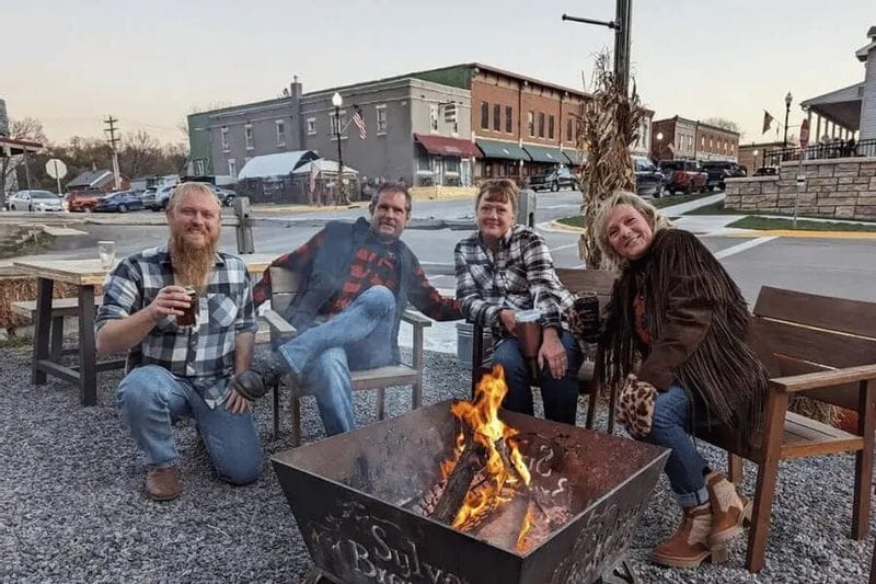 People gather around a fire pit outside Sylvan Brewing in downtown Lanesboro, Minnesota, on a fall evening.