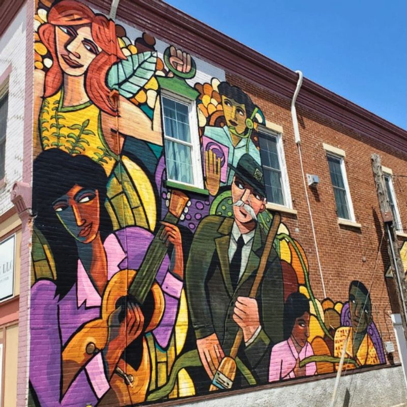 A colorful mural painted on the side of a brick building in downtown Lanesboro, depicting musicians and performers in a stylized, vibrant design that reflects the town’s arts and cultural heritage.