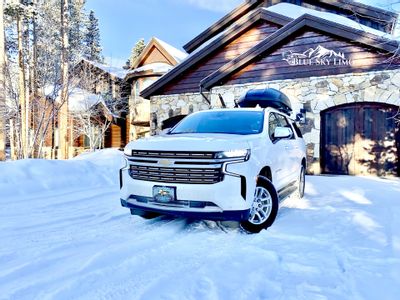 Blue Sky Limo private shuttle SUV with a rooftop ski box parked in a snowy Summit County driveway after a transfer from Denver Airport